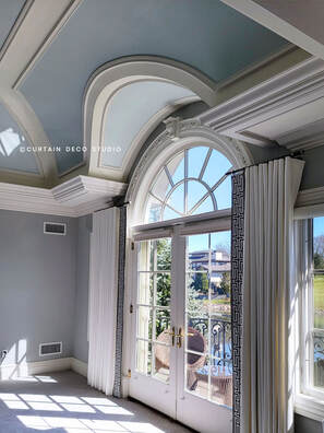 Close-up view of the elegant arched window in Alpine, NJ, highlighting the sophisticated semi-classic style with white curtains and detailed architectural moldings.