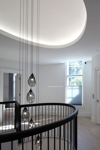 Staircase Area with Modern Lighting;Elegant staircase area with modern pendant lighting and a window featuring Hunter Douglas shades, creating a stylish and well-lit space.