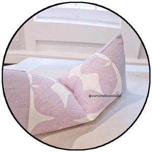 Custom made pillow with a light purple and white pattern on a white table near a window.