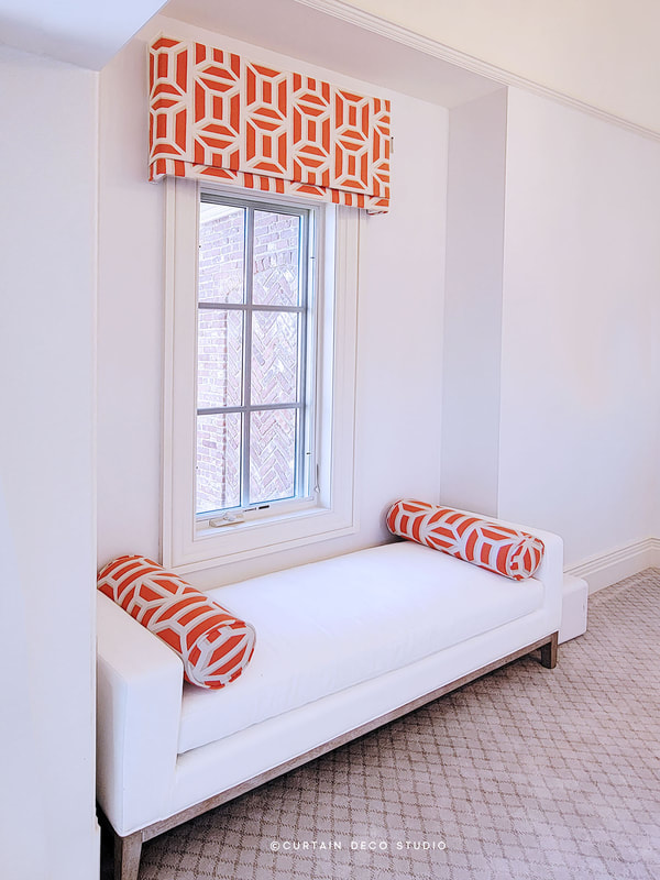 Stylish room in Alpine, NJ, featuring a window with a bold orange and white geometric valance. The white bench beneath the window is accented with matching orange and white bolster pillows, creating a modern and vibrant look.